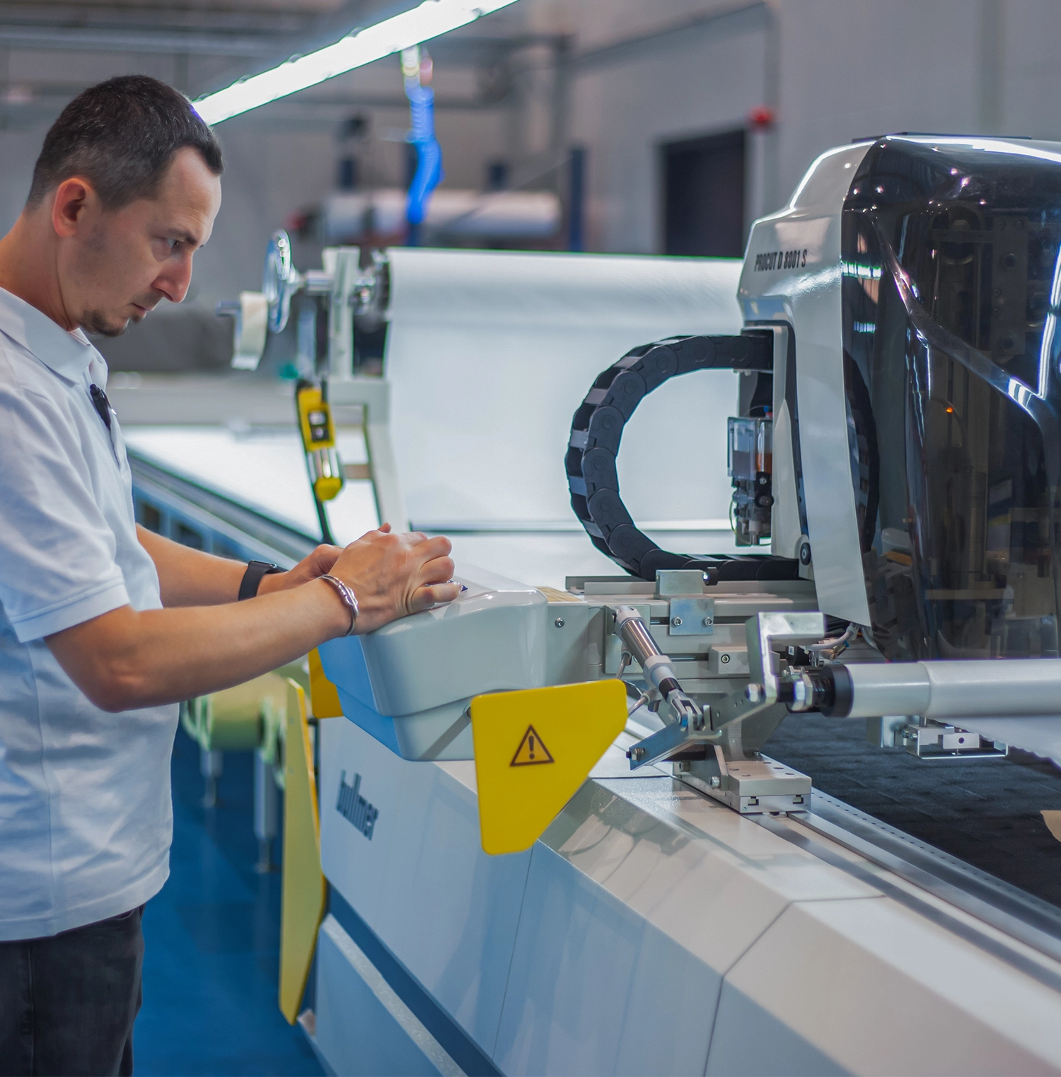 An operator working at an industrial fabric-cutting machine.