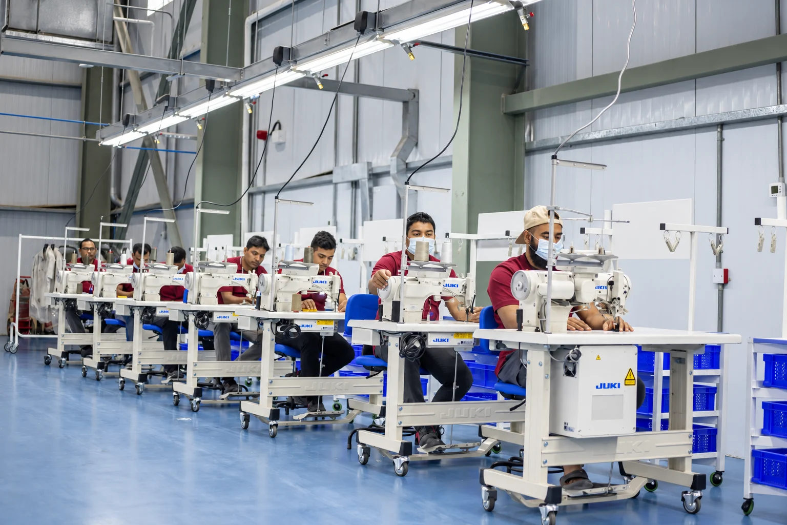 Operators working at industrial sewing stations in a textile factory.